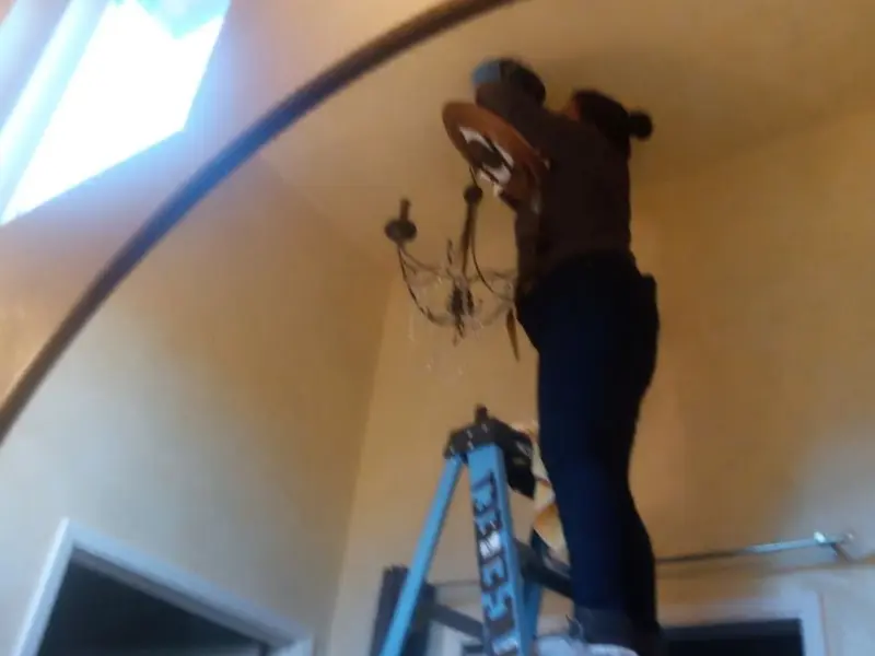 Electrician installing a chandelier in a Sadsbury residence